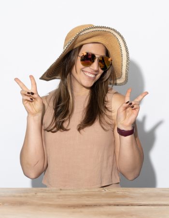 Kiersten Lucas wearing a sun hat and holding up peace signs